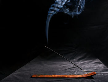 Close-up of cross on table against black background