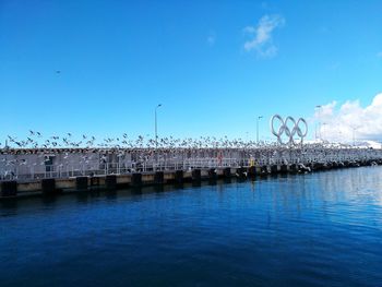 Sea by buildings against blue sky