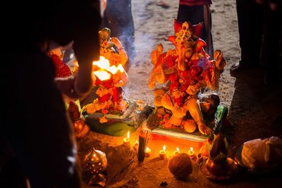 Midsection of person worshipping to ganesha at night
