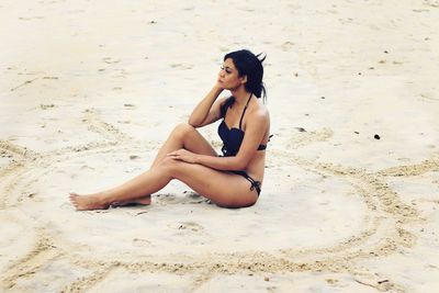 Portrait of young woman sitting on sand at beach