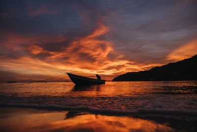 Boat moored on sea against sky during sunset