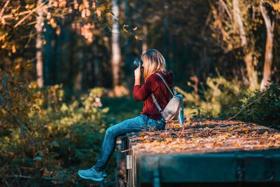 Side view of woman sitting in forest