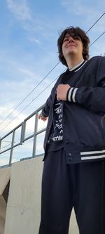 Low angle view of young man standing against sky