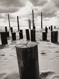 Close-up of wooden posts on beach against sky