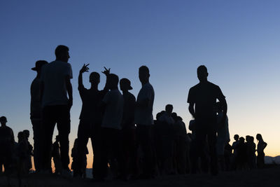 Silhouette people standing against clear sky during sunset