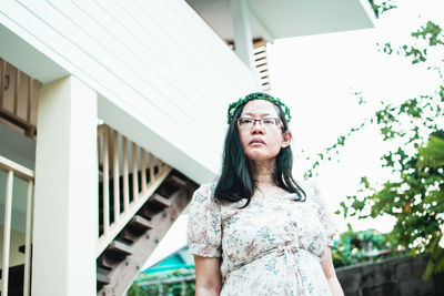 Portrait of young woman standing against building
