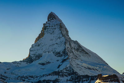 Low angle view of snowcapped mountain against blue sky