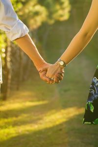 Cropped image of couple holding hands at park