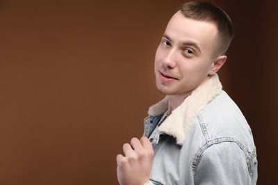 Portrait of young man looking away against black background