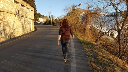 Rear view of woman walking on road