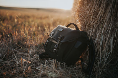 Close-up of bag by hay bale on field