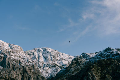 Low angle view of bird flying over mountain against sky