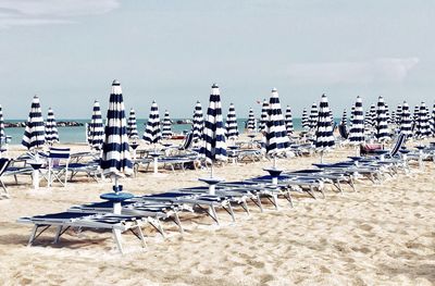 Row of chairs on beach against sky