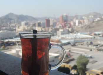 Close-up of coffee on glass against buildings in city