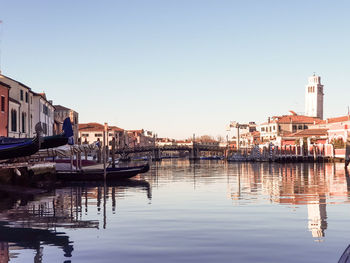 Sailboats moored in river against buildings in city