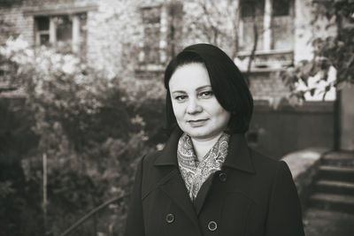 Portrait of woman standing outside house