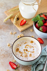 Healthy breakfast - whole grain flakes, milk and fresh strawberries on stone or slate background. 