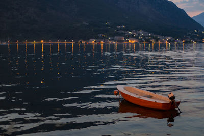 Boat moored by lake against sky during sunset