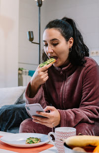 Young woman eating food at home