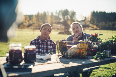 Thoughtful male and female farmers with organic vegetables on table at market