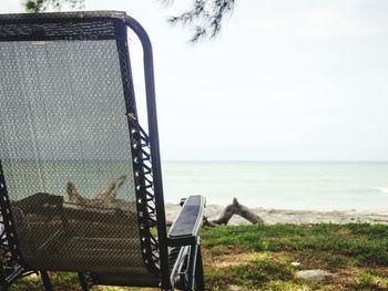 Chair on beach against sky