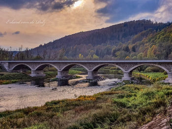 Arch bridge over river against sky