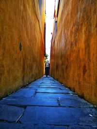 Rear view of woman standing in narrow alley along buildings