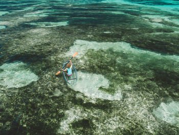 Rear view of woman canoeing in sea against sky