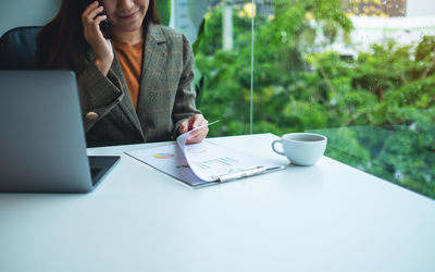 Woman using laptop while sitting on table