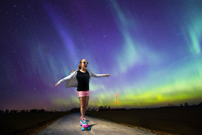 Girl skateboarding against star field at night