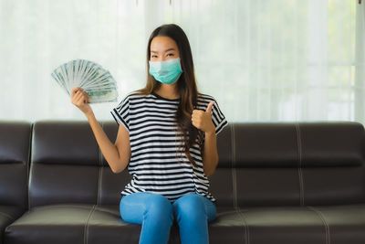 Full length of woman sitting on sofa at home