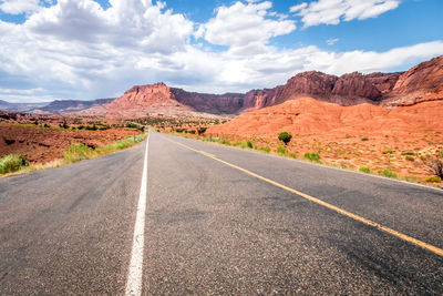 Empty road by mountains against sky