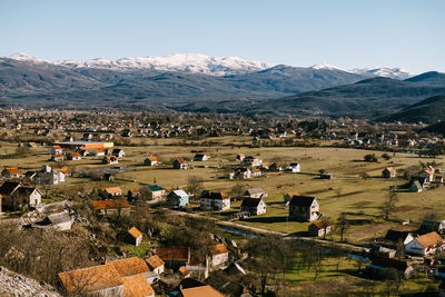 Aerial view of houses on field by mountains against sky