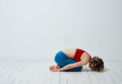 Full length of woman sitting on hardwood floor