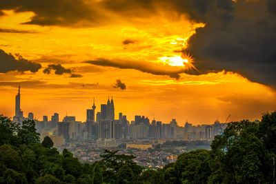 Scenic view of buildings against cloudy sky during sunset