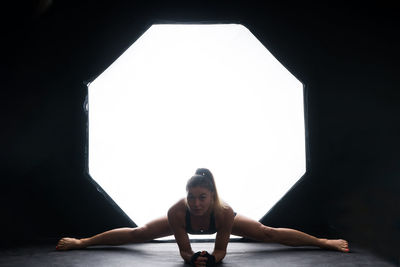 Low angle view of young woman sitting against clear sky