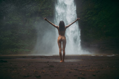 Young woman standing against waterfall