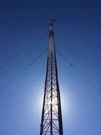 Low angle view of radio pylon against clear blue sky