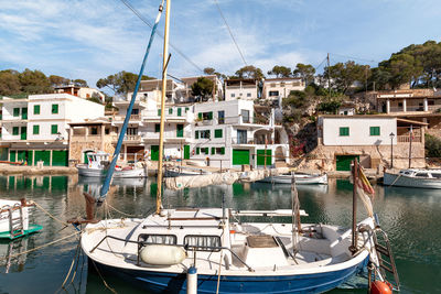 Sailboats moored in harbor by buildings against sky