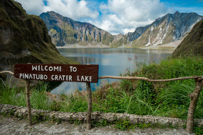 Information sign by mountains against sky