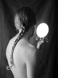 Black and white view of a young beautiful woman holding a mirror with no reflection.