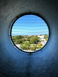 Trees and houses seen through window in wall