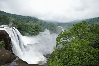 Scenic view of waterfall in forest against sky