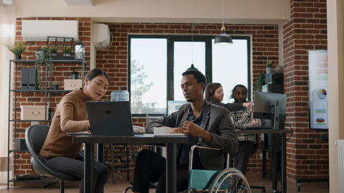 Young woman with man using laptop at office