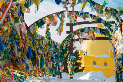 Prayer flags with tibetan mantras in wind at snowy temple complex, asian culture at local monastery