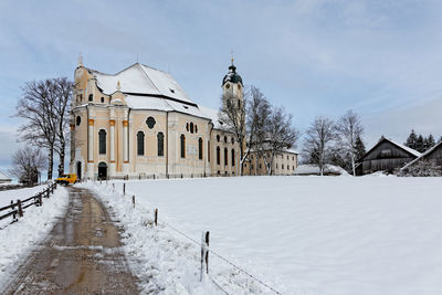 Empty road amidst snow covered field leading towards wies church at winter