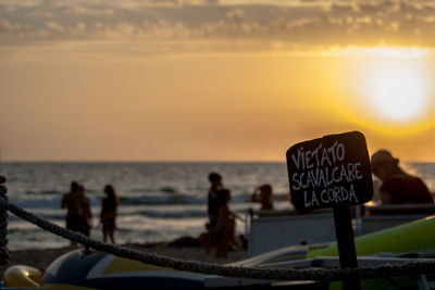 Signboard on beach at sunset
