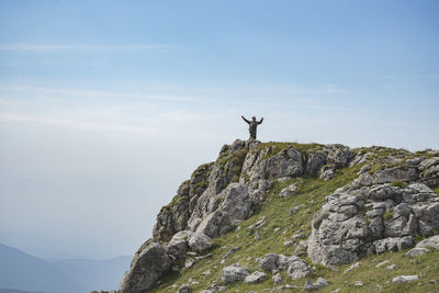 Low angle view of person on rock against sky