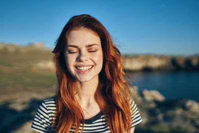 Portrait of smiling young woman against sky