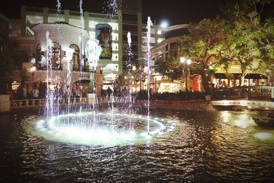 Illuminated fountain in city at night